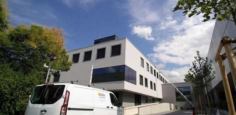 Weißer Transporter mit Schölles-Logo vor einem großen hellen Neubau