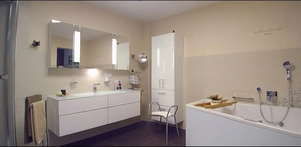Fertiges Bad mit hellem Waschtisch, Spiegelschrank, Hochschrank und Badewanne