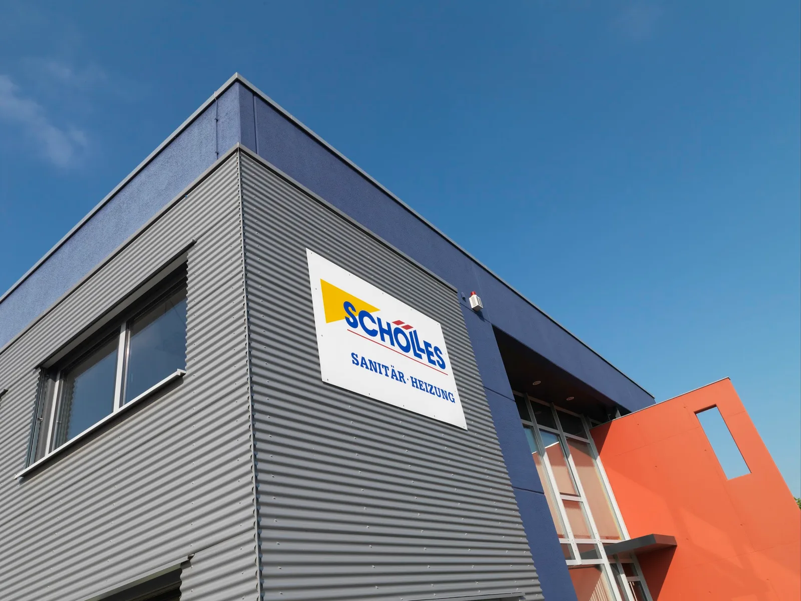 Firmengebäude von Schölles mit großem Schild Schölles Sanitär Heizung und rotoranger Fassadenfläche